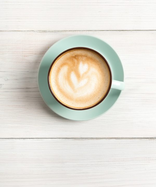 Cappuccino foam, coffee cup top view on white wood background